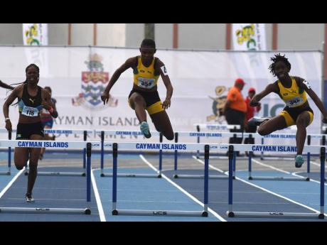 Jamaica’s Sashell Reid (centre) and Quaycian Davis (right) storm by the Bahamas’ Reshae Dean on their way to gold and silver, respectively, in the Girls Under 17 400m hurdles final at the Carifta Games, in the Cayman Islands on Sunday, April 21, 2019.