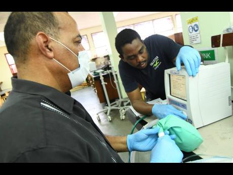 Dr Paul Aiken (left), CEO of Mona-Tech Engineering Services Ltd, and engineer Dontae Rodney conducting repairs to ventilators and other medical equipment for the public health sector at The University of the West Indies, Mona Faculty of Engineering, on Monday.