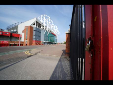 A padlocked gate stands near the closed Manchester United stadium, Old Trafford, in Manchester, northern England, as the English Premier League football season has been suspended due to the coronavirus.