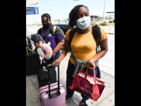 University of the West Indies, Mona, students from Antigua Akilah Southwell (left) and Stevika Foster of Montserrat prepare to board a flight yesterday at the Norman Manley International Airport. Both of them were among a group of students who were repatriated to their respective countries after being stranded in Jamaica owing to the COVID-19.