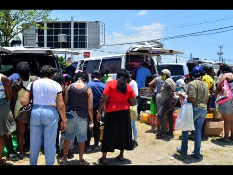 A number of persons gather at the Portmore Mall roundabout to purchase ground provisions and other produce at a scaled-down farmers’ market.