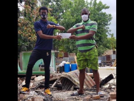 Portmore United’s Romaine Breakenridge (left) handing over a cheque to Waterhouse and National goalkeeper Akeem Chambers at the latter’s burnt out home in Olympic Gardens yesterday. 