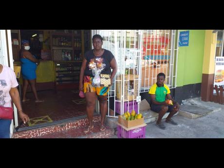 Food vendor Michelle McFarlane, who claims her goods were damaged by the municipal police, stands near a shop on Harbour Street in Port Antonio.