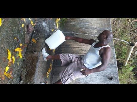 Derrick Myrie catching water from a source in his community. 