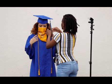 
Anderson High School senior Teyaja Jones (left) prepares to be photographed in her cap and gown and a bandanna face cover on Tuesday, May 5, 2020, in Austin, Texas. Texas’ stay-at-home orders due to the COVID-19 pandemic have expired and Texas Governor Greg Abbott has eased restrictions on many businesses that have now opened, but school buildings remain closed. 