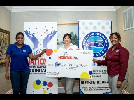 Food For The Poor’s Development and Marketing Manager Marsha Burrell-Rose (left) and Director Kivette Silvera (right) accept a comprehensive symbolic cheque to cover the construction of 10 homes from Christine Scott-Brown, CEO of the National Baking Company Foundation.