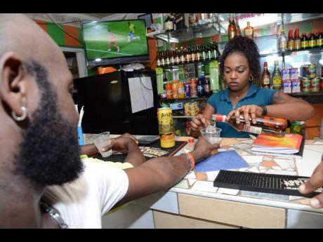  A bartender pours a drink for a patron at  a community bar in Stony Hill, St Andrew, in 2018. After a two-month ban, the Government will allow the reopening of bars next week.