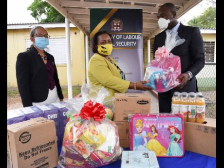 Zavia Mayne (right), state minister in the Ministry of Labour and Social Security, hands over clothing, food, toiletries and other supplies to Rosalee Gage-Grey, chief executive officer of the Child Protection and Family Services Agency, during a ceremony at the Glenhope Place of Safety in Kingston on Tuesday. Looking on is Colette Roberts-Risden, permanent secretary in the Ministry of Labour and Social Security. 