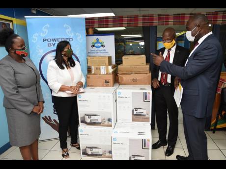 Zavia Mayne (right), state minister in the Ministry of Labour and Social Security, looks at ICT equipment handed over by the Universal Service Fund (USF) to the Jamaica Council for Persons with Disabilities (JCPD) on Tuesday at the JCPD’s St Andrew offices. Looking on are (from left) Kaydian Smith-Newton, principal director, Ministry of Science, Energy and Technology, representing portfolio minister Fayval Williams; Dr Gunjan Mansingh, chairperson, USF; and Daniel Dawes, chief executive officer, USF. 