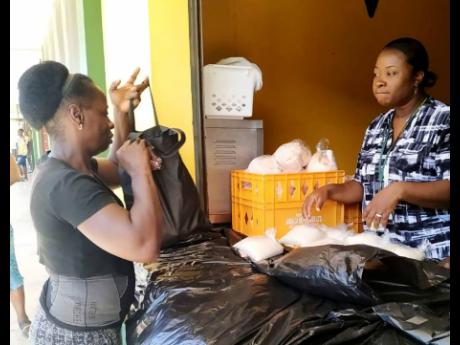 Dr Tracy Brown-Coote (right), principal of Petersfield High School in Westmoreland, talks with a parent while distributing food packages recently.