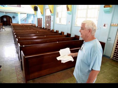 Brother Bernie Spitzley, church administrator walks by empty  benches inside the Holy Rosary Roman Catholic Church in East Kingston yesterday. He was at the church preparing for service tomorrow where some 72 members will be accommodated at any one time for service.