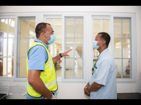 Minister of Health and Wellness Dr Christopher Tufton (left) in dialogue with Senior Medical Officer Dr Glenton Stratchan at the Annotto Bay Hospital in St Mary on Saturday, May 9. Opposition Spokesman Dr Morais Guy has taken the ministry's COVID-19 testing regime to task.