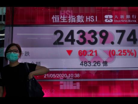 A woman wearing a face mask walks past a bank’s electronic board showing the Hong Kong share index at Hong Kong Stock Exchange Thursday, May 21, 2020. Asian stock markets are mixed after Wall Street rose amid Chinese trade tension with Washington and Australia. Investors looked ahead to Friday’s meeting of China’s legislature for details of possible new steps by Beijing to stimulate its virus-battered economy.(AP Photo/Vincent Yu)