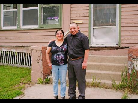 In this May 23, 2020 photo, Paulina and Marcos Francisco pose for a photo in front of their house in Sioux City, Iowa. They bought the home after years of working in a meatpacking plant and other food-processing jobs. 