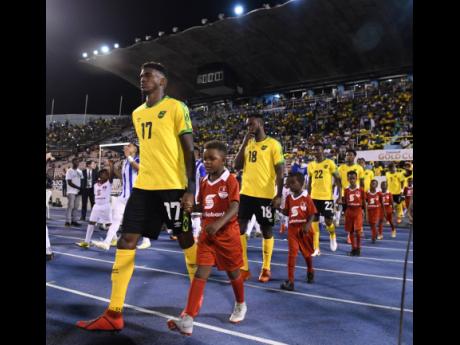 Damion Lowe (foreground) and other members of the Reggae Boyz team making their way on to the field ahead of Jamaica’s match against Honduras in the Concacaf Gold Cup at the National Stadium in 2019.