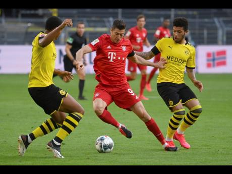 Munich’s Robert Lewandowski (centre) and Dortmund’s Jadon Sancho (right) challenge for the ball during the German Bundesliga match between Borussia Dortmund and FC Bayern Munich in Dortmund, Germany, yesterday. Bayern won 1-0.