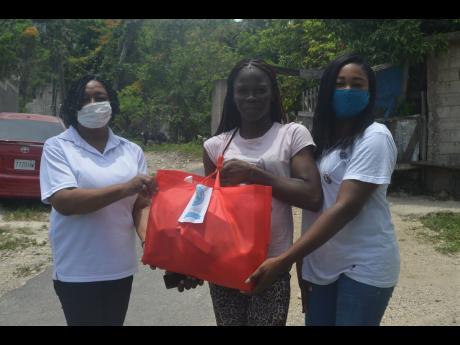 Shantel Brown (centre), mother of six-year-old Cory-Ann Palmer of Norwood, St James, receives a care package from Shamara Brissett-Gordon (right), convener of the Quality Education Circle 36 (QEC 36) team from the Ministry of Education’s Region Four, and