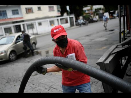 A worker wearing a face mask amid the new coronavirus pandemic fills one of the tanks of a state oil company gas station in Caracas, Venezuela, on Sunday, May 31. 