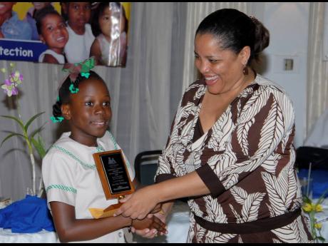 Eight-year old Lori-Ann Mullings of Excelsior Primary School receives an award from Alison McLean, then CEO of the Child Development Agency, at the National Child Month Committee 2007 Community Service Awards ceremony at the Alhambra Inn in Kingston.
