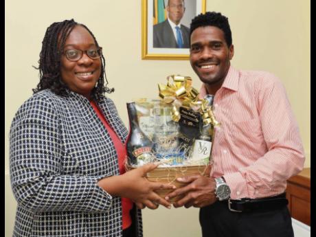 Joan Lugg, Sagicor client, receives her special 50th birthday gift, courtesy of Sagicor Group, from her insurance adviser, Jason Lobban.
