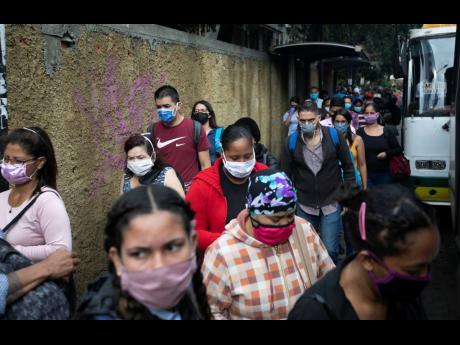 Pedestrians and commuters wearing face masks amid the new coronavirus pandemic crowd a sidewalk near a bus stop in Caracas, Venezuela on Monday. (AP)