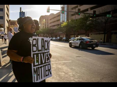 Sydnee Harris of Omaha, Nebraska, joins dozens of others staging a rally, holding a Black Lives Matter poster outside the Omaha Douglas Civic Center in Omaha on Wednesday.
