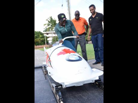 National female bobsledder Carrie Russell (left) shows off her sled to Sports Development Foundation General Manager Denzil Wilks and Jamaica Bobsled and Skeleton Federation President Nelson Stokes during a training session at the GC Foster College of Phys