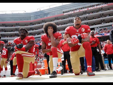 In this file photo from October 2016, San Francisco 49ers outside linebacker Eli Harold (left), quarterback Colin Kaepernick (centre), and safety Eric Reid kneel during the national anthem before an NFL game against the Dallas Cowboys in Santa Clara, Calif