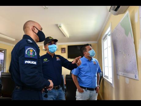 National Security Minister Dr Horace Chang (centre), Commissioner of Police Major General Antony Anderson (left) and Minister without Portfolio Matthew Samuda examine a map at the Elletson Road Police Station on Saturday. 