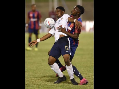 Richard Thompson (left) from Jamaica College (JC) holds off a challenge from Kaman Davis from St Andrew Technical during the 2019 ISSA Manning Cup football final. JC won 5-4 on penalties to win the title.