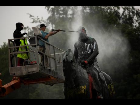 Workers clean graffiti from a statue of Belgium’s King Leopold II in Brussels, yesterday, that was targeted by protesters during a Black Lives Matter demonstration.  Leopold is increasingly seen as a stain on the nation where he reigned from 1865 to 1909