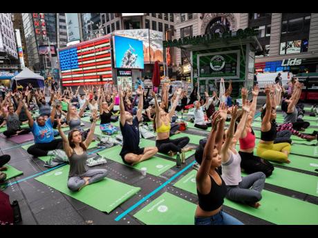 People participate in the Mind Over Madness yoga event to celebrate the summer solstice during a rainstorm in New York’s Times Square, Friday, June 21, 2019.