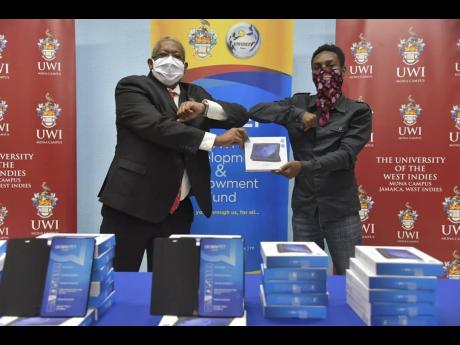 Principal of The University of the West Indies, Professor Dale Webber (left), hands over a recently donated tablet to a student.