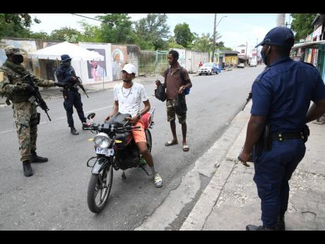 Security forces stop commuters at an SOE checkpoint on North Street, Kingston, on Sunday. There are SOEs in half of the country’s 19 police divisions.