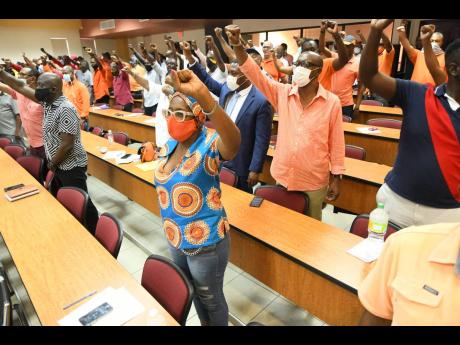 PNP prospective candidates raise their fists during a special conference at the Faculty of Law Lecture Theatre at The University of the West Indies on Sunday.