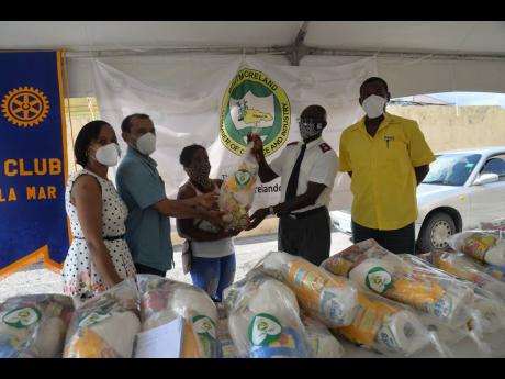 President of the Westmoreland Chamber of Commerce and Industry, Moses Chybar (second left) and Major Robert Ewart (second right), of the Salvation Army Church, deliver a care package to a resident of Savanna-la-Mar (centre). Others looking on in photo are