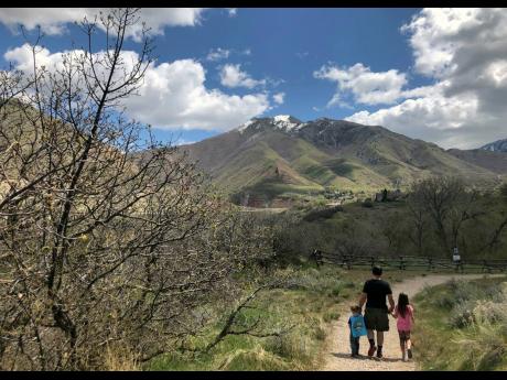 
In this April 22, 2020, photo, Associated Press journalist Lindsay Whitehurst’s husband, Dave Watson, walks with their two children on a trail in suburban Salt Lake City. When the coronavirus pandemic hit, Watson suddenly became a full-time dad. Outside