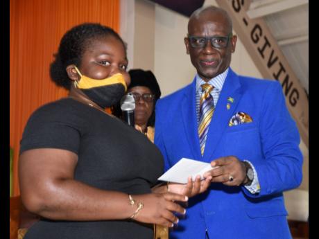 Desmond McKenzie, minister of local government and community development, hands over a cheque to Jael Nelson, beneficiary of the Edward Seaga Foundation, to fund her university tuition. The presentation was made during a Father’s Day service in honour of
