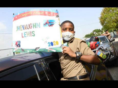 Rudolph Brown/Photographer
Jhevaughn Lewis holds up the Class of 2020 banner at the Dunrobin Primary School’s drive-through graduation ceremony yesterday at the school in Kingston. 