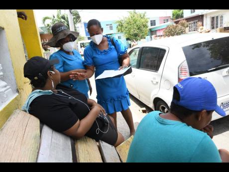 Health workers of the Ministry of Health and Wellness in discussion with a resident of Tivoli Gardens yesterday during a community surveillance exercise in the area. 