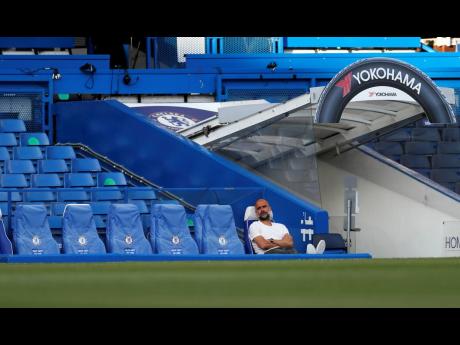 Manchester City head coach Pep Guardiola sits on the bench ahead of their English Premier League match against Chelsea at Stamford Bridge, in London, England, on Thursday.