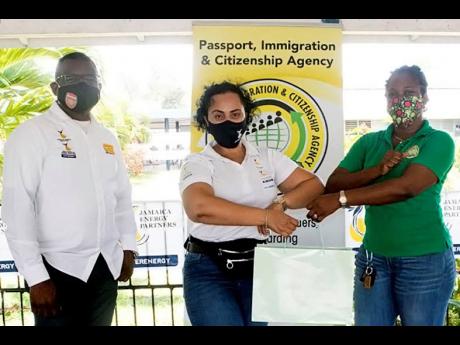 From left: President and Chief Executive Officer of the Jamaica Energy Partners Group, Wayne McKenzie, shares lens with Melissa Newman, corporate responsibility manager and project lead for the annual JEP Health & Wellness Fair, as she accepts a token from