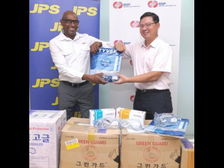 Joseph Williams (left), senior vice-president, generation, Jamaica Public Service (JPS), and former JPS board member and chairman, Ha Kyoung Song, bump elbows recently. The occasion was the handover to JPS of hazmat gear by major JPS shareholders, Korea, E