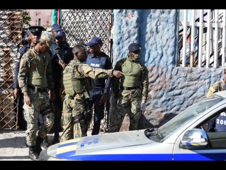 Members of the Jamaica Defence Force and the Jamaica Constabulary Force search a building along Fourth Street in Greenwich Town, Kingston, on Thursday. The community has been declared a zone of special operations from July 1 to July 14, 2020.