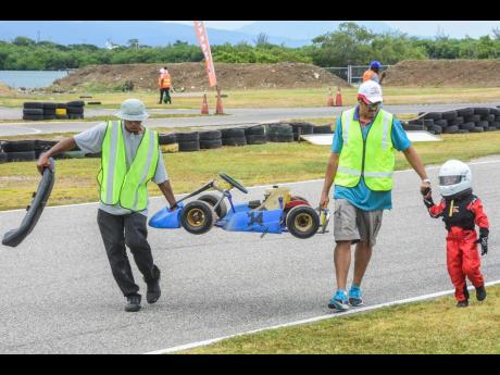 Marshals recovering a disabled kiddie kart and karter after a race.