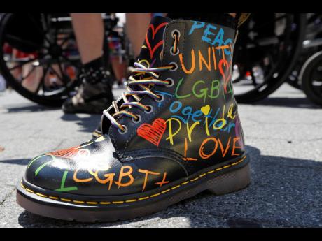 
A person wears Pride-themed boots as they await the start of a queer-liberation march for Black Lives Matter and against police brutality on Sunday, June 28, 2020, in New York. 