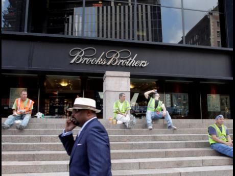 In this August 4, 2011 photo, a man passes a Brooks Brothers store on Church Street in New York’s financial district.