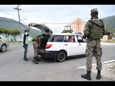 Members of the security forces conduct a search of a vehicle at a checkpoint in August Town, St Andrew, yesterday as a zone of special operation went into effect in the area.