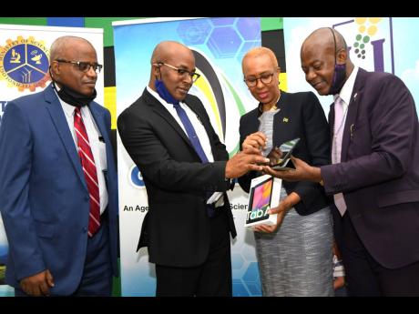 Fayval Williams, (second right) Minister of Science, Energy and Technology, looks at a tablet computer with from left Keith Smith, CEO of e-Learning Jamaica Company Limited; Anthony Grant, principal of Hope Valley Experimental School and Daniel Dawes, CEO 