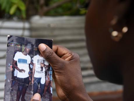A mother looks at a photo of her son who was shot and killed in Steer Town, St Ann recently.